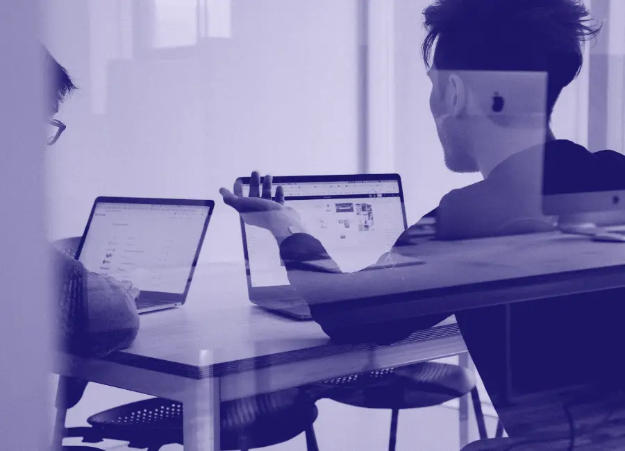 Two people working on laptops at a desk